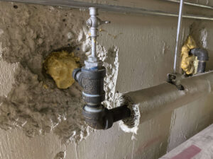 Hazardous materials removal in Calgary involving damaged insulation and exposed pipes in a pre-1990s home
