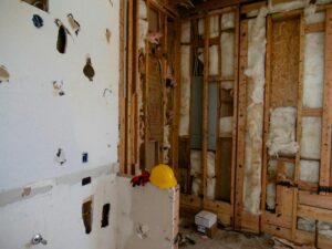 Interior demolition area with exposed wall studs, insulation, and partially removed drywall