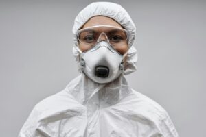Certified abatement worker wearing respirator, goggles, and full protective suit for asbestos or mold removal